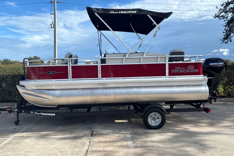 The Image of 2026 Sun Tracker Bass Buggy 18 DLX pontoon boat on trailer, featuring Mercury outboard motor. - 0