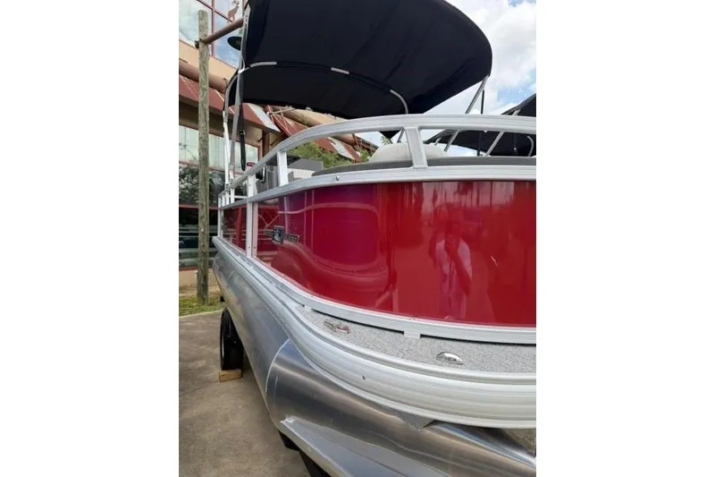 Slide: The Image of 2026 Sun Tracker Bass Buggy 18 DLX pontoon boat with red exterior and black canopy. - 2