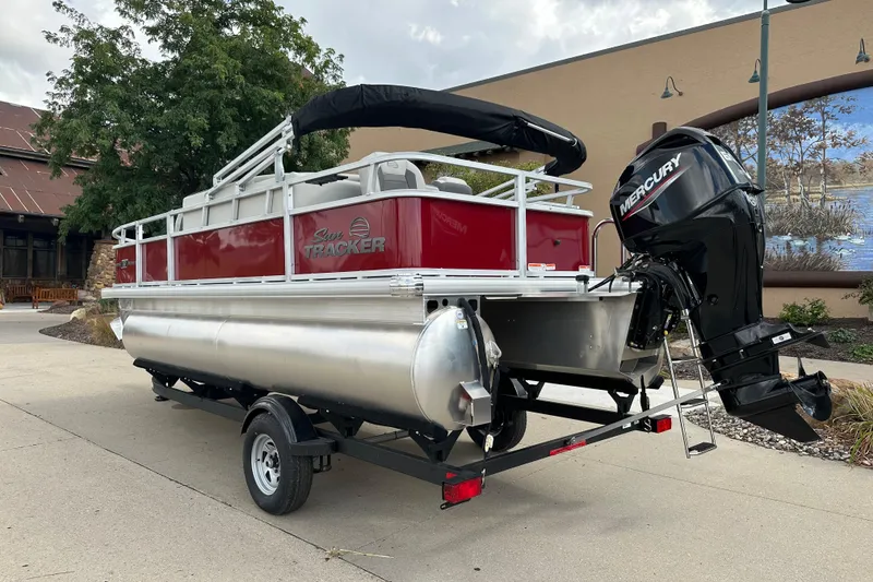 Slide: The Image of 2026 Sun Tracker Bass Buggy 18 DLX pontoon boat with Mercury outboard motor on trailer. - 2
