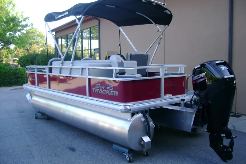 Slide: The Image of 2026 Sun Tracker Bass Buggy 18 DLX pontoon boat with Mercury 75 engine, parked outdoors. - 2