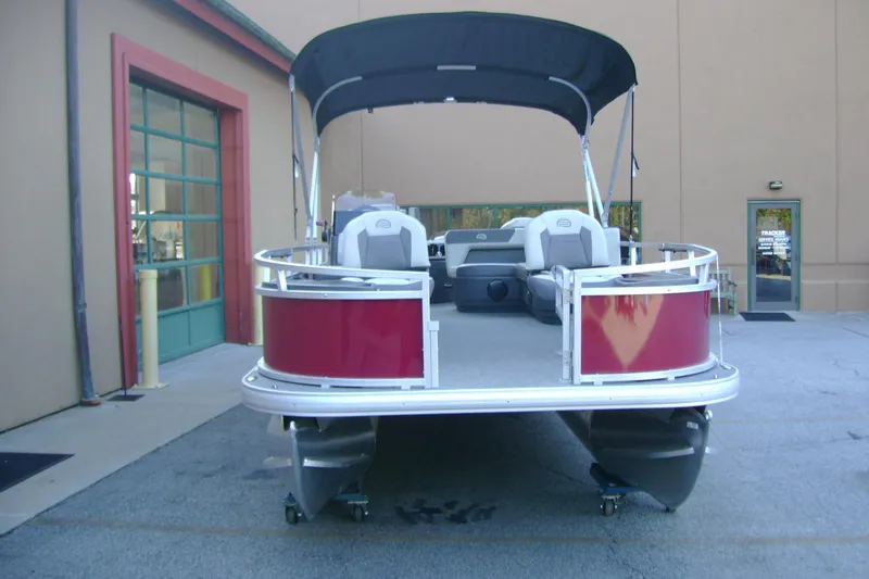 Slide: The Image of 2026 Sun Tracker Bass Buggy 18 DLX pontoon boat with canopy, parked outside a building. - 3
