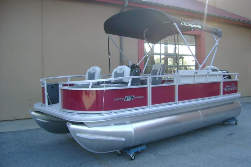 Slide: The Image of 2026 Sun Tracker Bass Buggy 18 DLX pontoon boat with canopy, parked outdoors. - 1