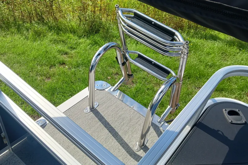 Slide: The Image of 2026 Sun Tracker Bass Buggy 18 DLX boat ladder on grassy background. - 14