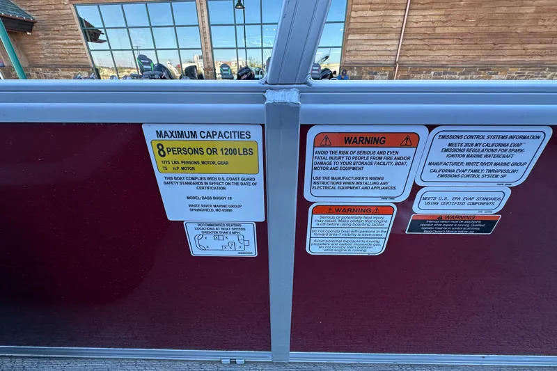 Slide: The Image of 2026 Sun Tracker Bass Buggy 18 DLX capacity and warning labels on boat interior. - 23