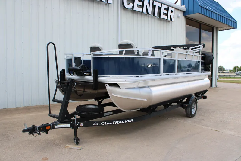 Slide: The Image of 2026 Sun Tracker Bass Buggy 18 DLX pontoon boat on trailer outside dealership. - 1