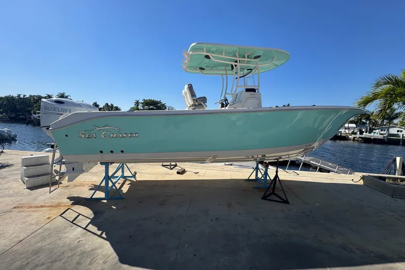 Slide: The Image of 2023 Sea Chaser 27 HFC CC boat on stands by waterfront, clear sky. - 3