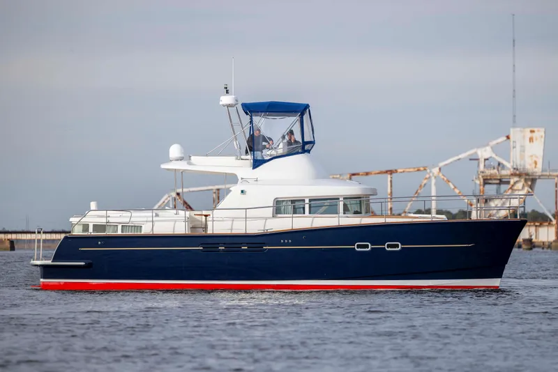 Slide: The Image of 2004 Lagoon 43 PC yacht with blue hull and red trim on calm water. - 10