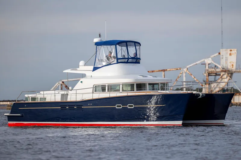 Slide: The Image of 2004 Lagoon 43 PC yacht with blue hull, cruising on calm waters. - 12