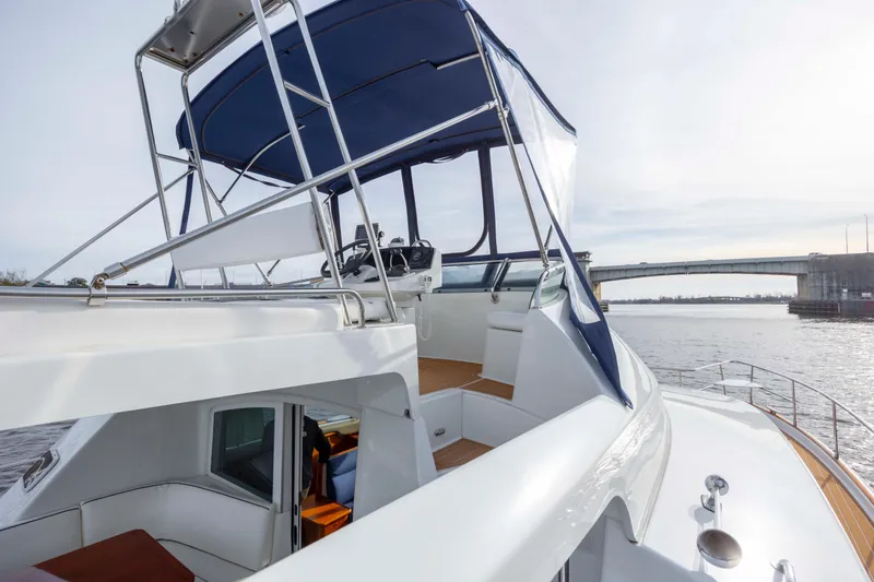 Slide: The Image of 2004 Lagoon 43 PC yacht with blue canopy, docked near a bridge on a sunny day. - 26