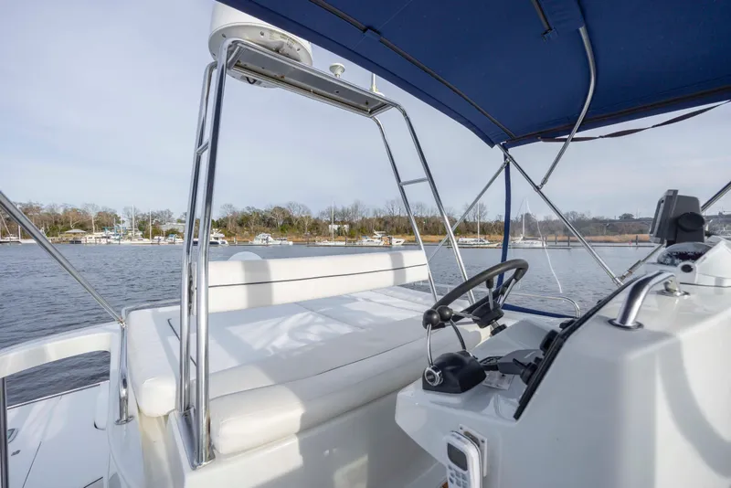 Slide: The Image of 2004 Lagoon 43 PC yacht helm with blue canopy, overlooking serene waters and distant shoreline. - 31