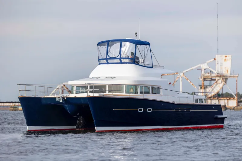 Slide: The Image of 2004 Lagoon 43 PC catamaran cruising on water, featuring a sleek blue and white design. - 4