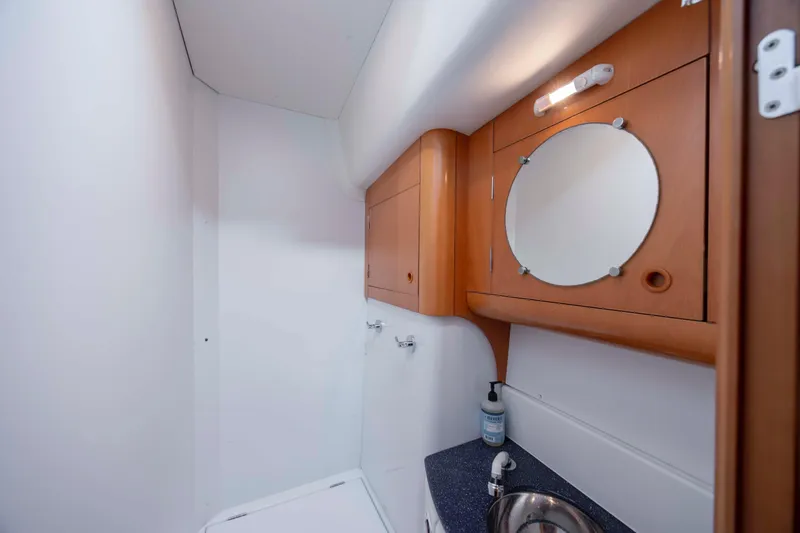 Slide: The Image of Bathroom interior of 2004 Lagoon 43 PC yacht with wooden cabinetry and round mirror. - 50