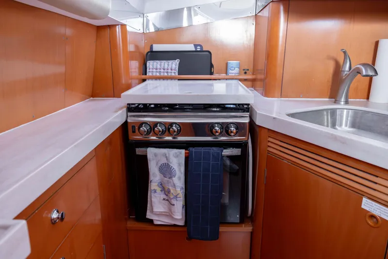 Slide: The Image of Galley kitchen in 2004 Lagoon 43 PC yacht with stove, sink, and wooden cabinetry. - 61