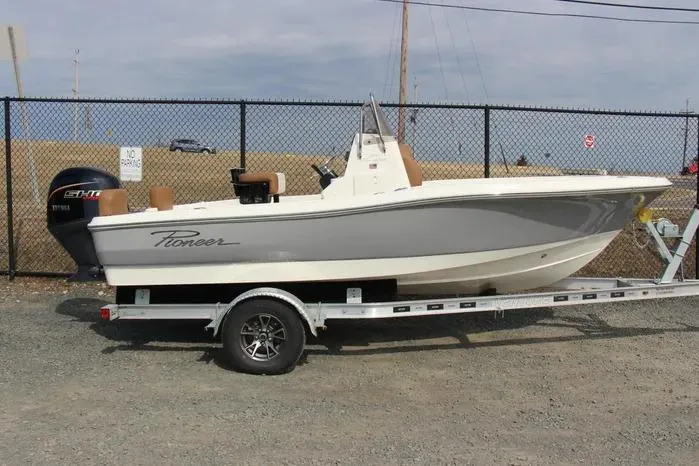 The Image of 2025 Pioneer 180 Sportfish boat on trailer, gray and white design, parked outdoors. - 0