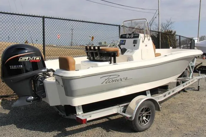 Slide: The Image of 2025 Pioneer 180 Sportfish boat on trailer with Yamaha engine, parked near a fence. - 3