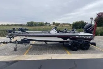 Slide: The Image of 2017 Nitro Z21 boat parked on paved lot with residential buildings in background. - 2