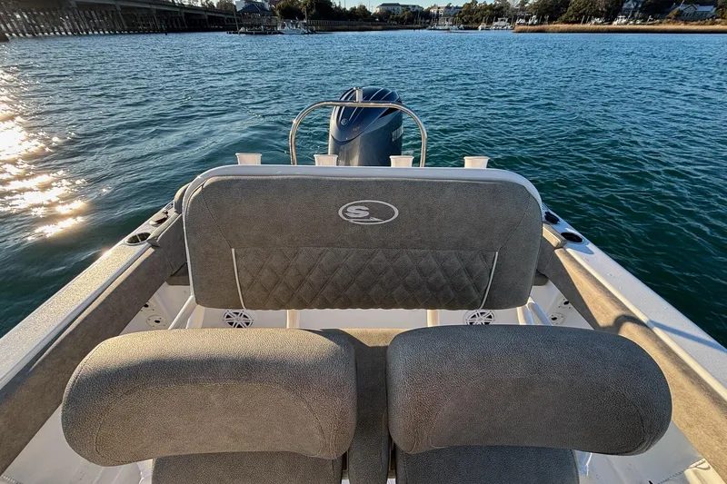 Slide: The Image of 2026 Sea Hunt Ultra 219 boat interior with cushioned seating on a sunny day. - 12