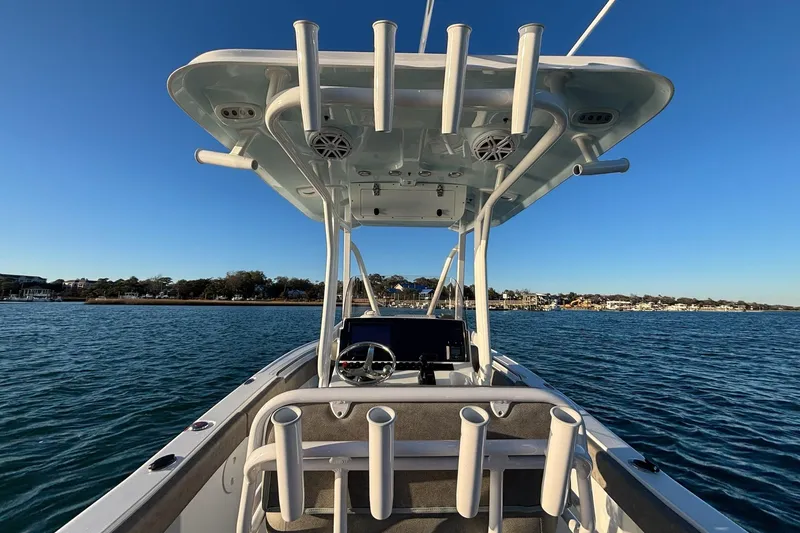 Slide: The Image of 2026 Sea Hunt Ultra 219 boat on water, featuring rod holders and console, under clear blue sky. - 14