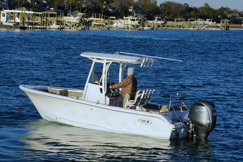 Slide: The Image of 2026 Sea Hunt Ultra 219 boat cruising on a calm blue lake near a marina. - 21