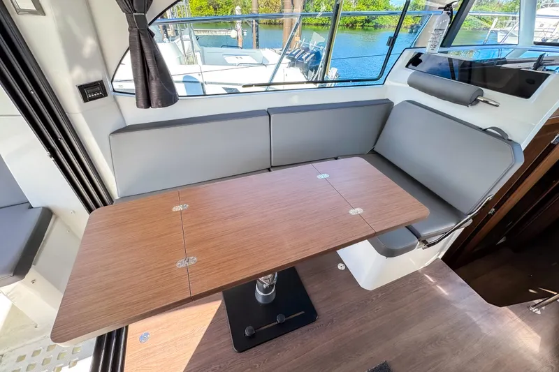 Slide: The Image of Interior of 2023 Beneteau Antares 11 with modern seating and wooden table. - 13