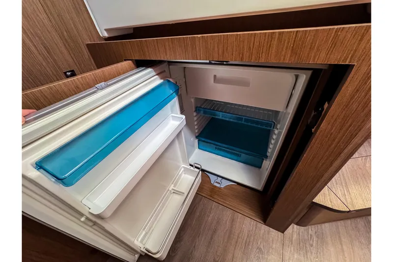 Slide: The Image of Open refrigerator inside 2023 Beneteau Antares 11 boat, featuring wooden cabinetry and modern design. - 34