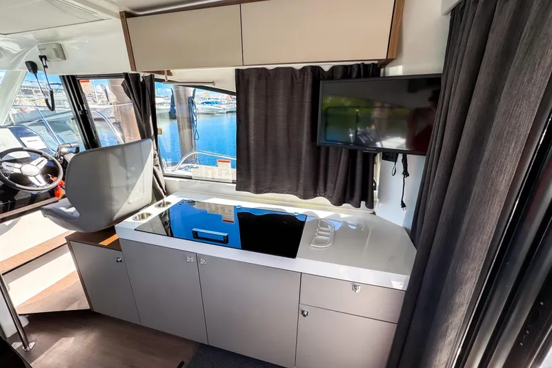 Slide: The Image of Interior of 2023 Beneteau Antares 11 with helm, kitchenette, and TV. - 8