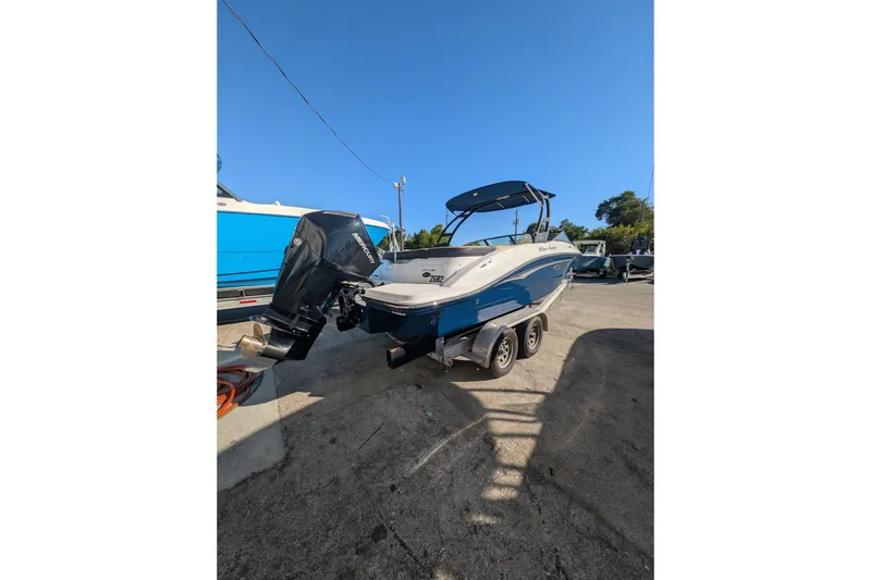 Slide: The Image of 2021 Sea Ray 21 SPX OB boat on trailer, blue and white, parked outdoors. - 2