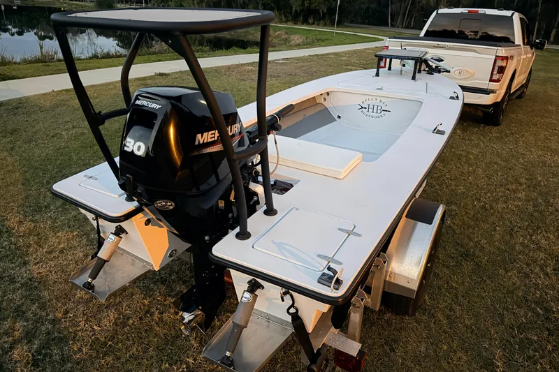 Slide: The Image of 2004 Hell's Bay Devilray boat with Mercury 30 engine on trailer, parked on grass. - 10