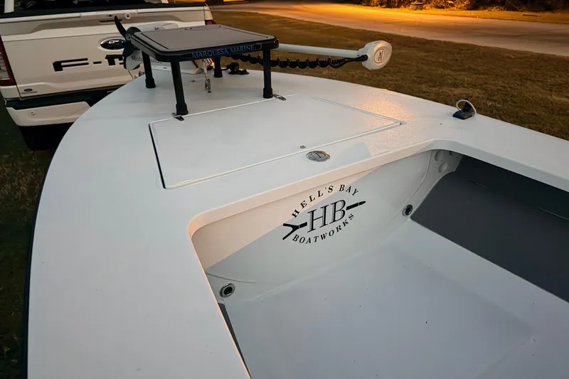 Slide: The Image of 2004 Hell's Bay Devilray boat with logo, parked near a Ford truck. - 13