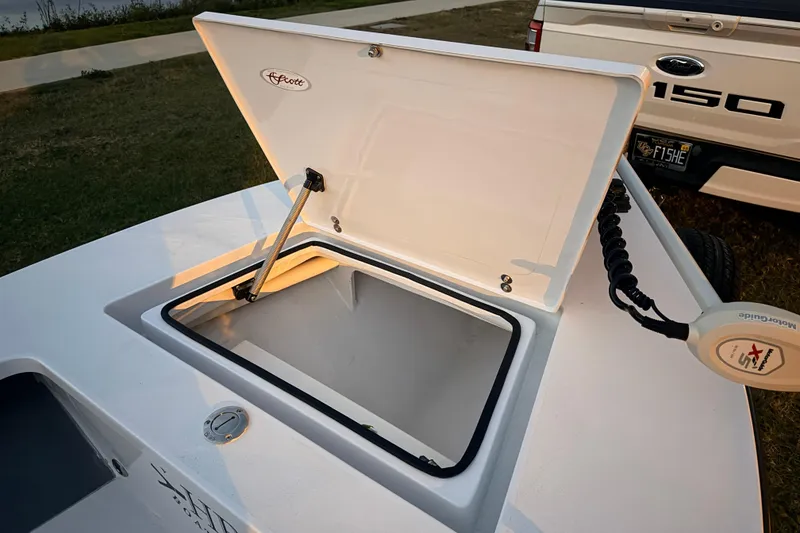 Slide: The Image of Open storage compartment on a 2004 Hell's Bay Devilray boat, parked near a Ford F-150. - 18