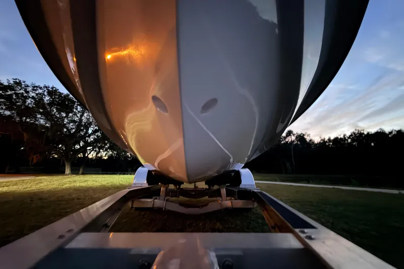 Slide: The Image of 2004 Hell's Bay Devilray boat on trailer at dusk, showcasing sleek hull design. - 6