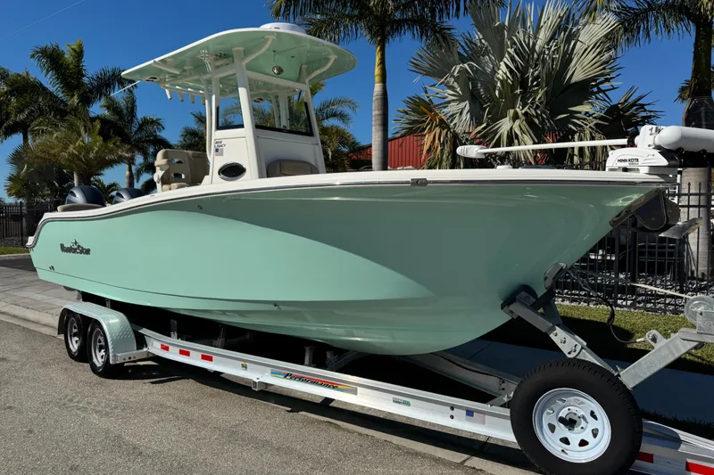 The Image of 2022 NauticStar 2602 Legacy boat on trailer, surrounded by palm trees. - 0
