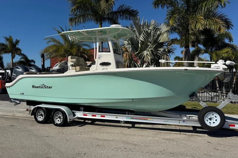Slide: The Image of 2022 NauticStar 2602 Legacy boat on trailer, parked near palm trees. - 2