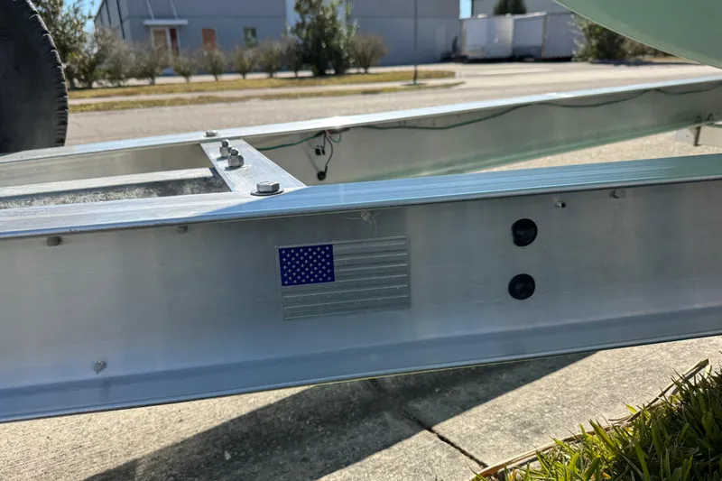 Slide: The Image of 2022 NauticStar 2602 Legacy boat on a Performance trailer, parked on grass. - 26