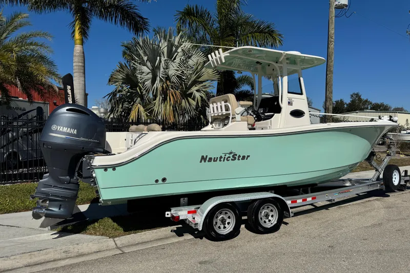 Slide: The Image of 2022 NauticStar 2602 Legacy boat on trailer, featuring Yamaha engine, parked near palm trees. - 3