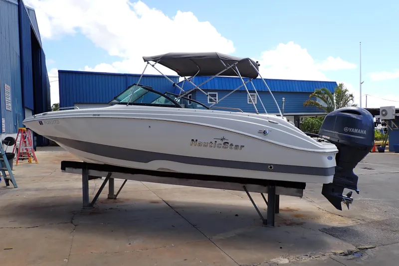 The Image of 2021 NauticStar 223 DC boat with Yamaha engine on display at a marina. - 0