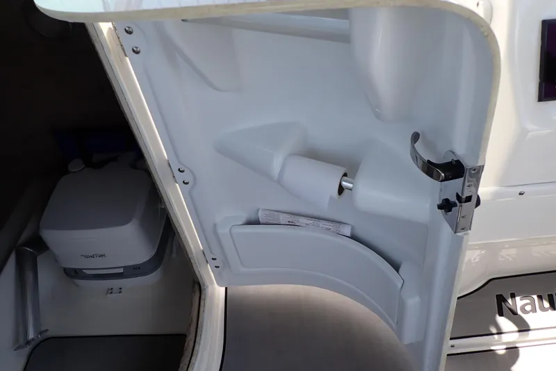 Slide: The Image of 2021 NauticStar 223 DC boat interior with storage compartment and portable toilet. - 28