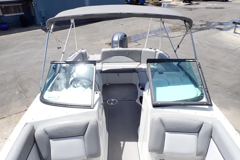 Slide: The Image of 2021 NauticStar 223 DC boat with bimini top and dual consoles, docked on concrete. - 6