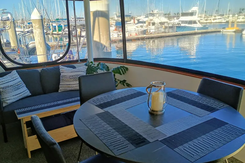 Slide: The Image of Interior of 1988 Vantare 46' Aft Cabin yacht with marina view, featuring cozy seating and table. - 41