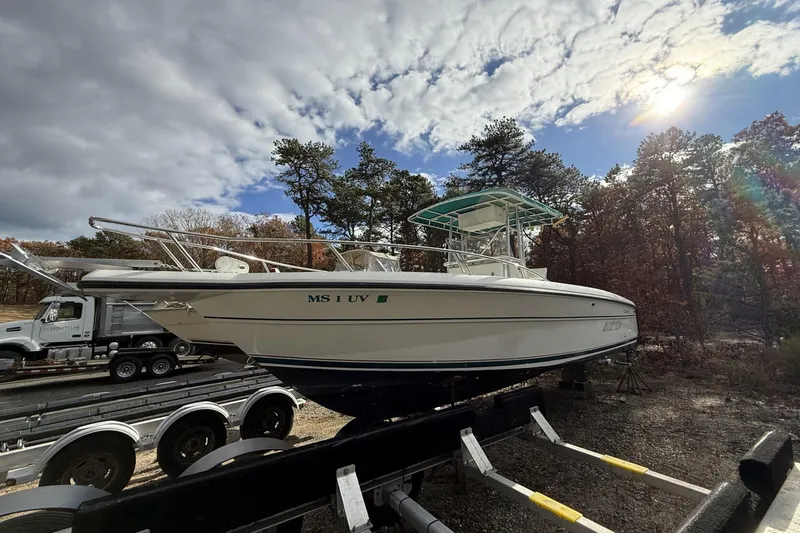 Slide: The Image of 1997 Stamas 270 Tarpon boat on trailer under cloudy sky, surrounded by trees. - 10