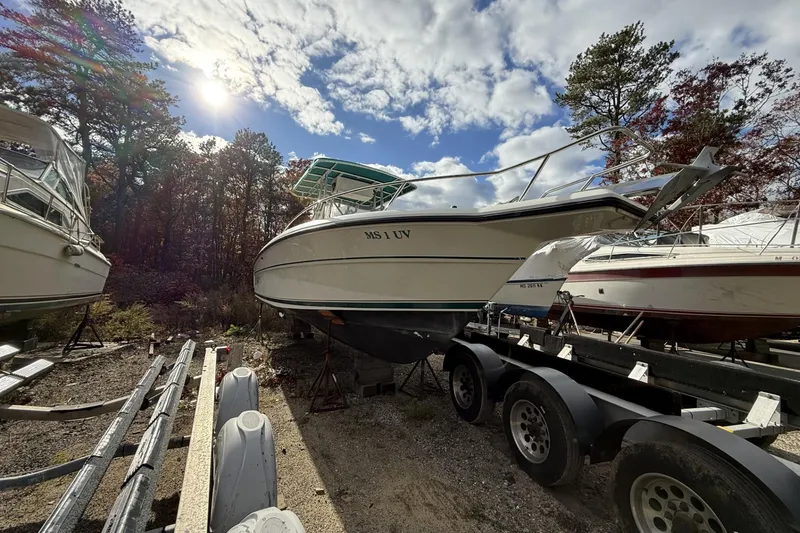 Slide: The Image of 1997 Stamas 270 Tarpon boat on trailer under sunny sky, surrounded by trees. - 8