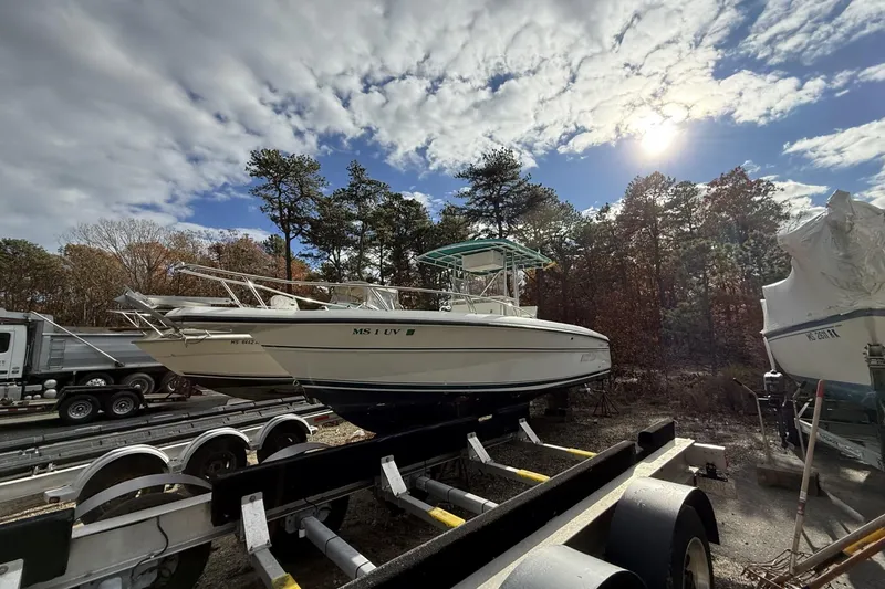 Slide: The Image of 1997 Stamas 270 Tarpon boat on trailer under sunny sky, surrounded by trees. - 9