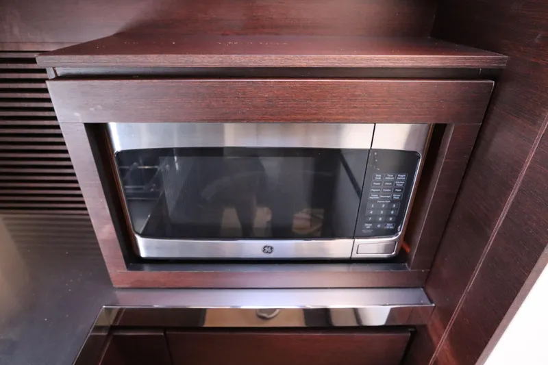 Slide: The Image of Built-in microwave in 2007 Azimut 62S yacht kitchen with dark wood cabinetry. - 50