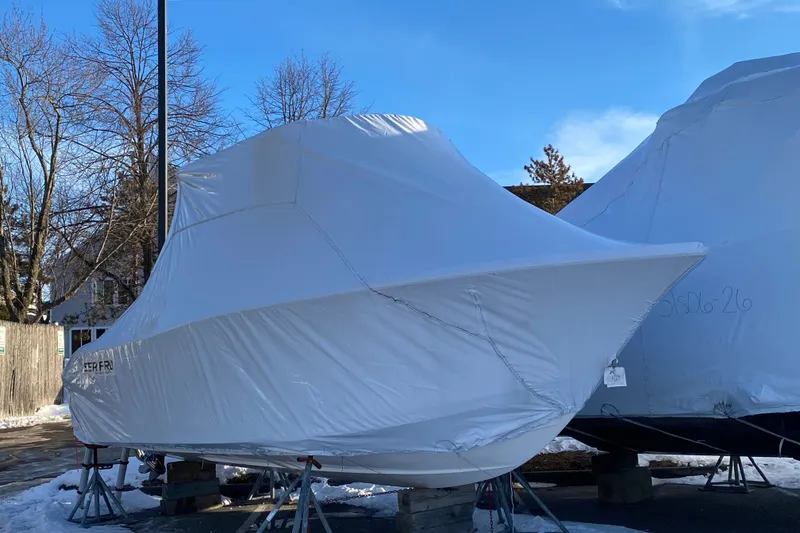 Slide: The Image of 2025 Sea Pro 222 Center Console boat covered in white tarp, stored outdoors. - 2