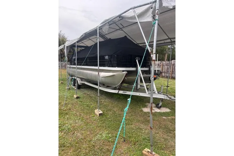 Slide: The Image of 2022 Veranda Vista 22RC pontoon boat under a protective canopy on a trailer. - 27