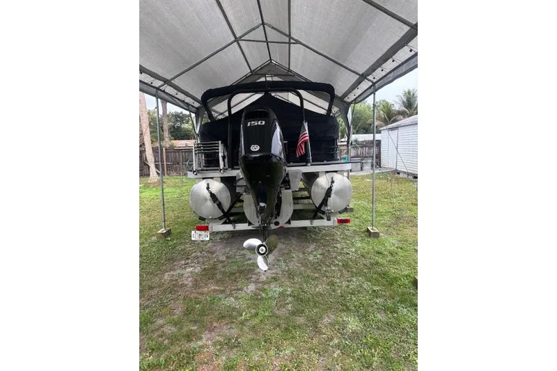 Slide: The Image of 2022 Veranda Vista 22RC boat under canopy, rear view with motor and American flag. - 30