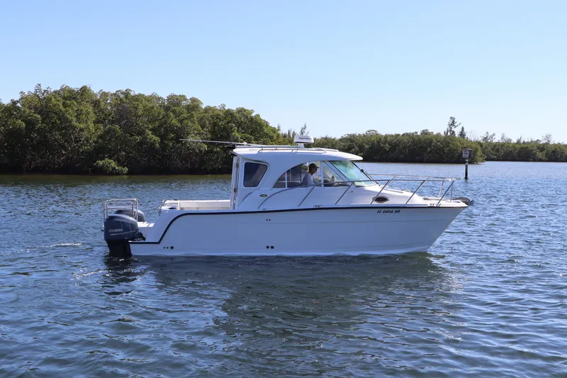 Slide: The Image of 2008 Glacier Bay 3080 Coastal Runner boat on calm water, near lush greenery. - 1