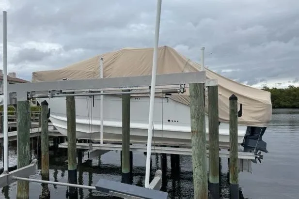 Slide: The Image of Covered 2008 Glacier Bay 3080 Coastal Runner on a boat lift, overcast sky. - 61