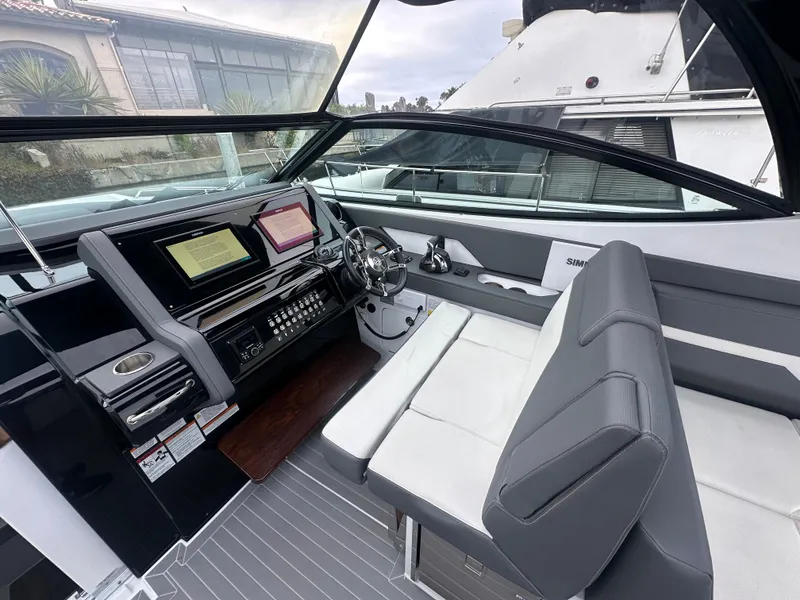 Slide: The Image of The image shows the cockpit of a 2021 Cruisers Yachts 38 GLS. It features modern instruments and gray upholstery. - 24