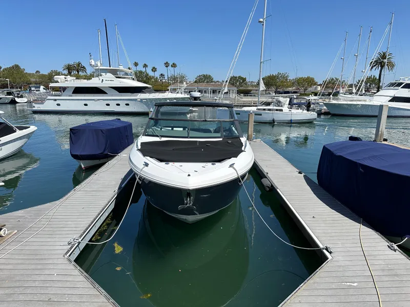 Slide: The Image of A 2021 Cruisers Yachts 38 GLS docked in a marina, surrounded by other boats. - 21